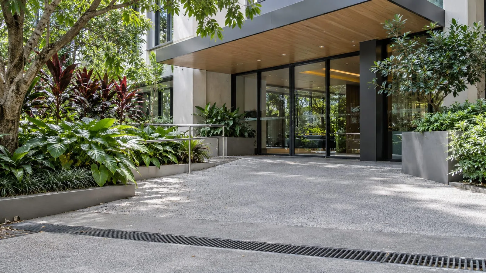 AI-generated illustration: Brisbane CBD commercial building entrance with a practical grated forecourt drain and subtropical street planting