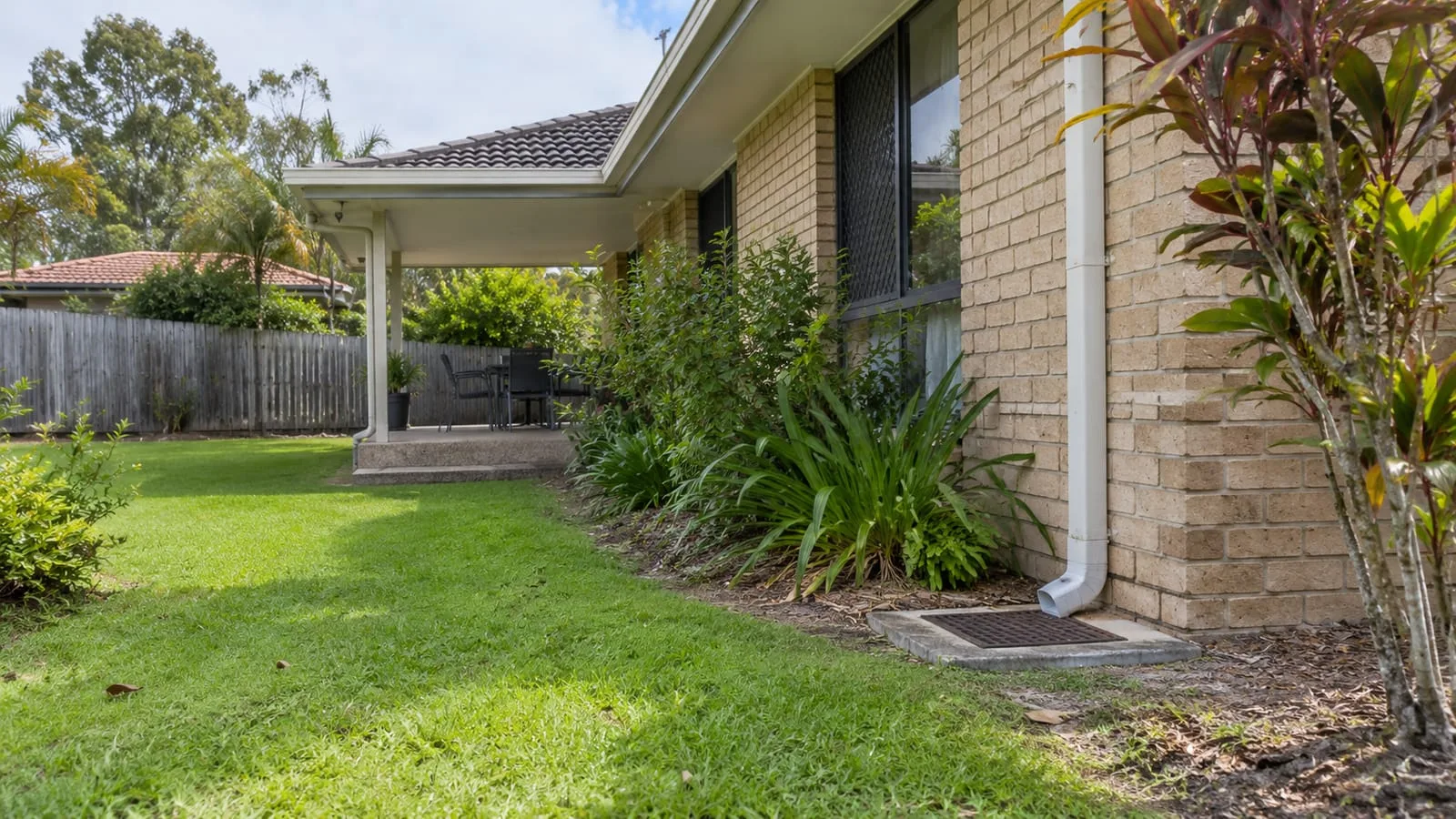 AI-generated illustration: Sunnybank established suburban home, garden and subtle stormwater pit and downpipe